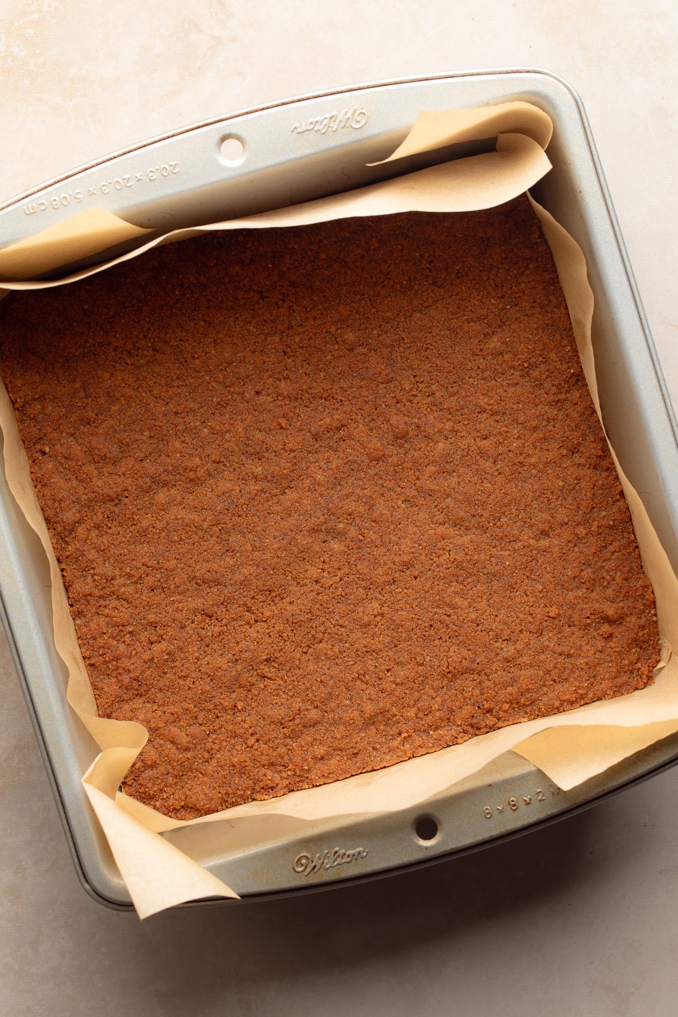 Overhead view of a baked Biscoff cookie crust in a baking pan.