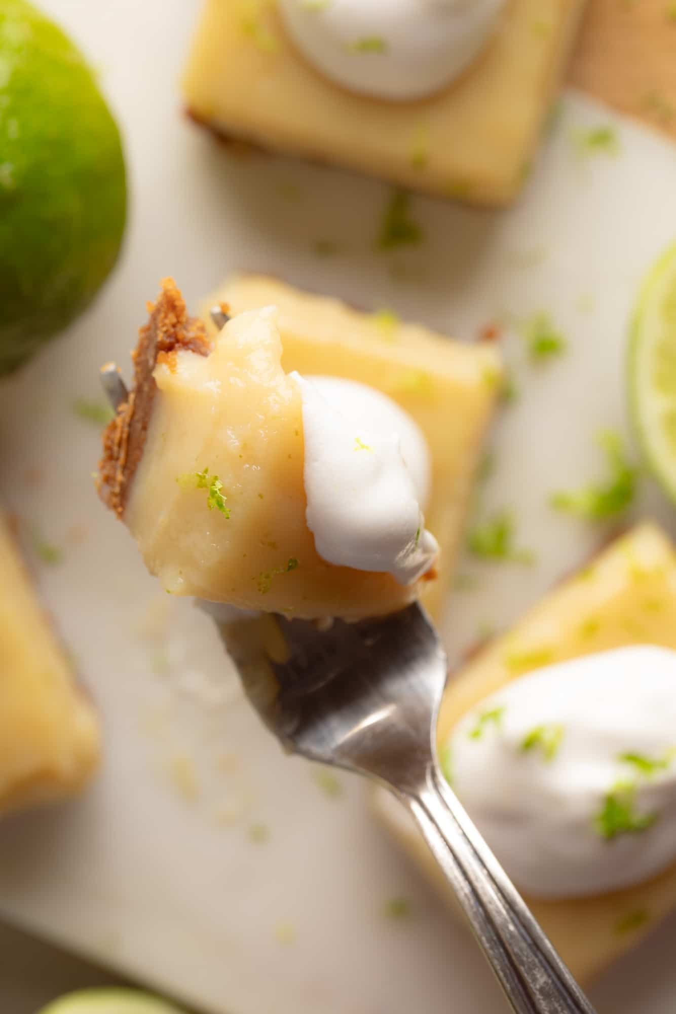 Overhead view of a fork, holding a bite of a vegan key lime pie bar.