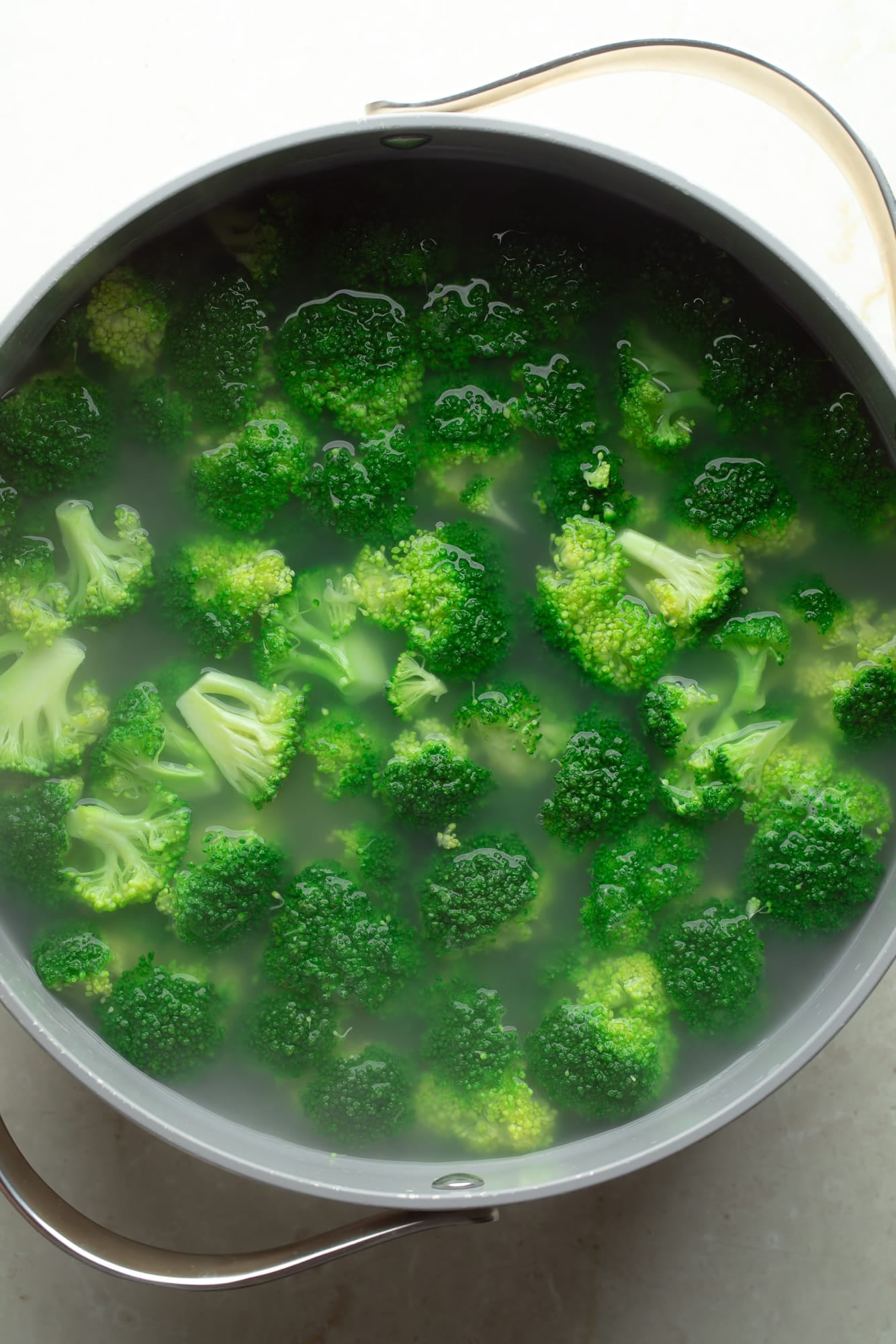 overhead view of broccoli cooking in a pot of hot water.
