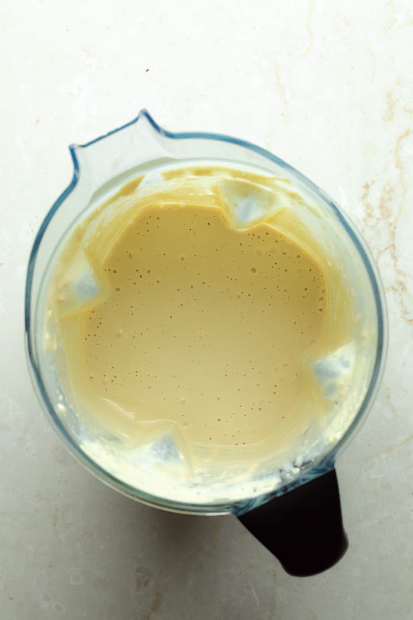 overhead view of a smooth white vegan cheese sauce in a blender.