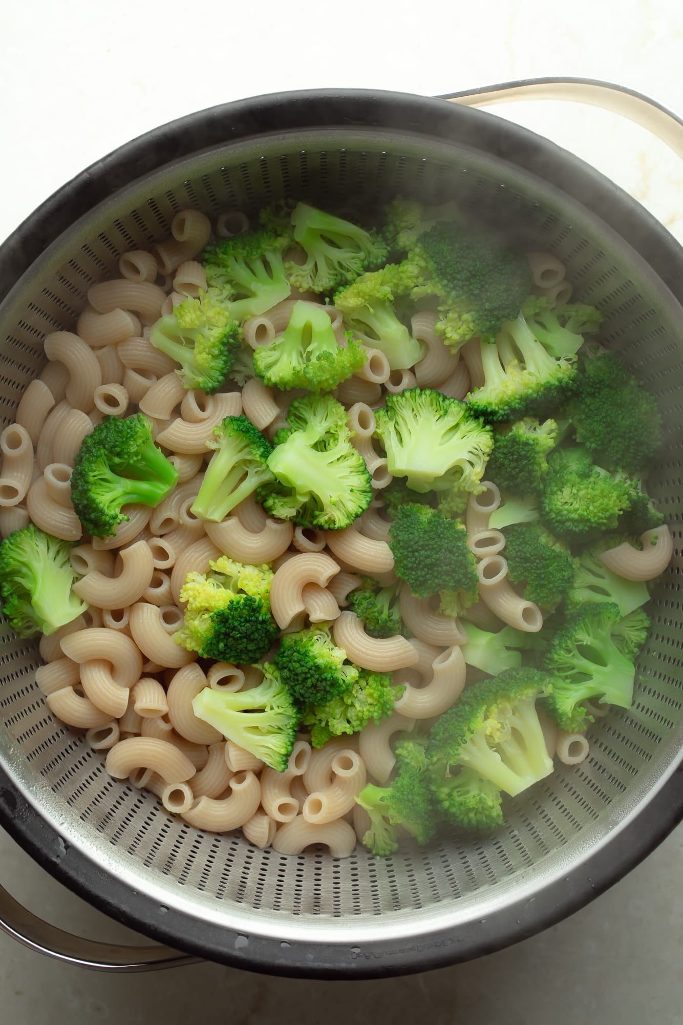 overhead view of a cooked pasta and broccoli in a colander.