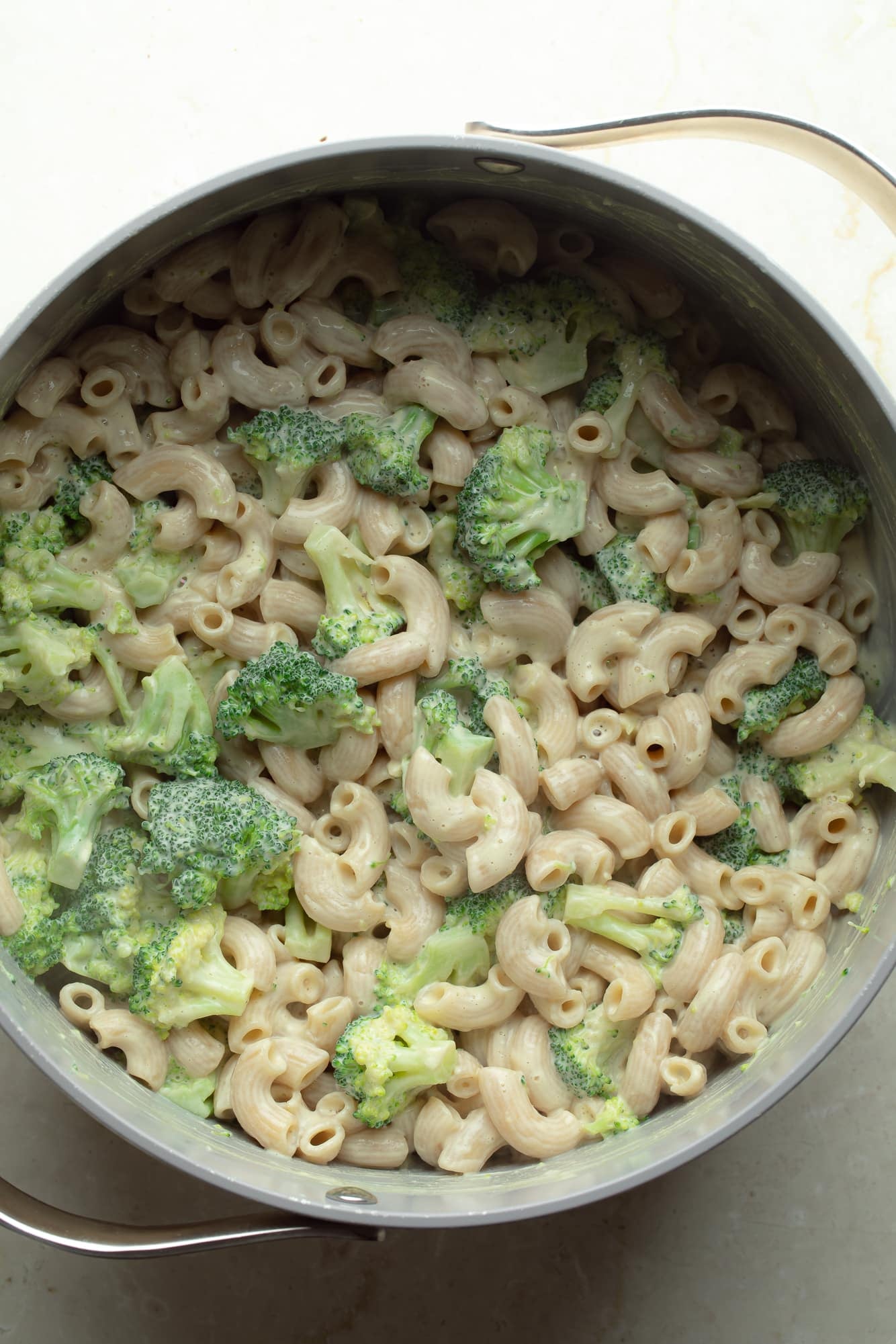 overhead view of vegan white mac and cheese with broccoli in a pot.