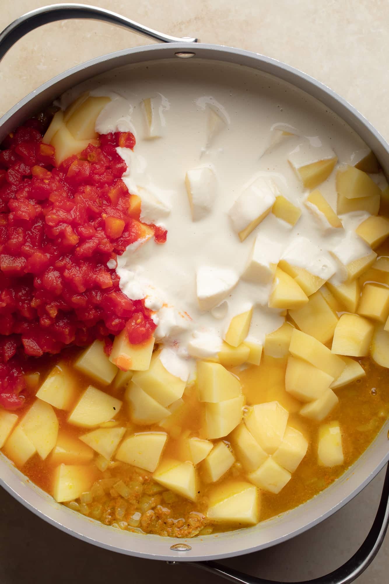 overhead view of the ingredients for vegan potato curry in a large pot.