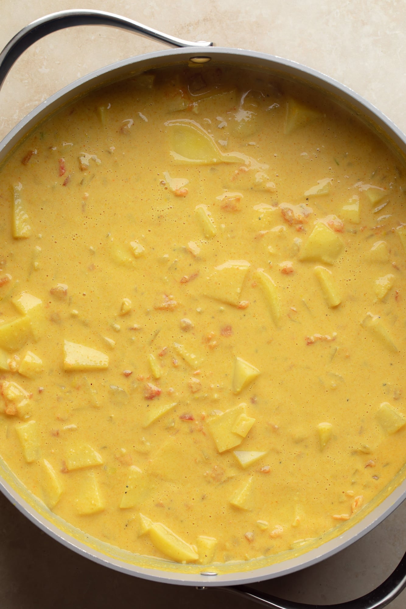 overhead view of vegan potato curry cooking in a large pot.