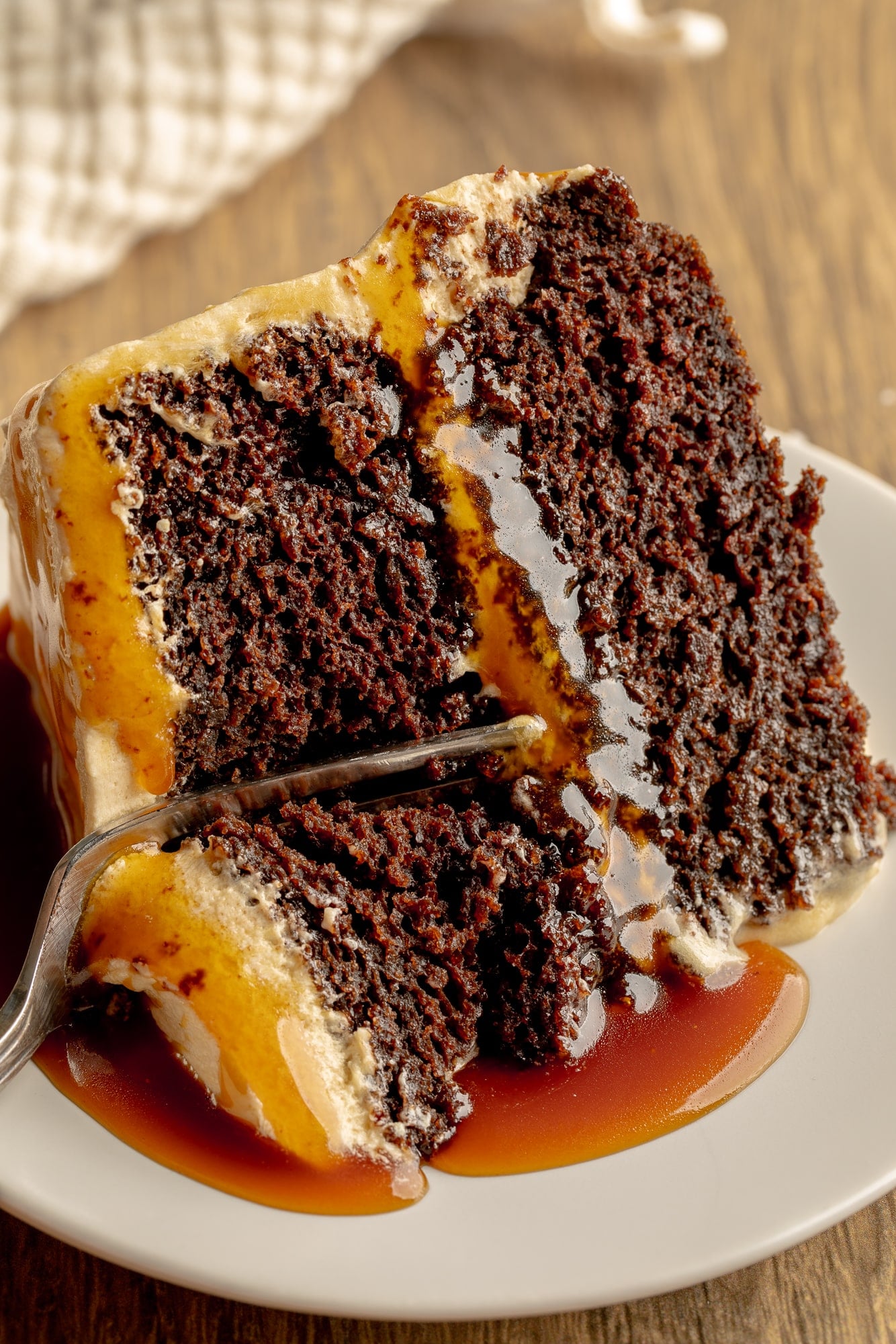 close up on a fork cutting into a slice of vegan salted caramel chocolate cake.