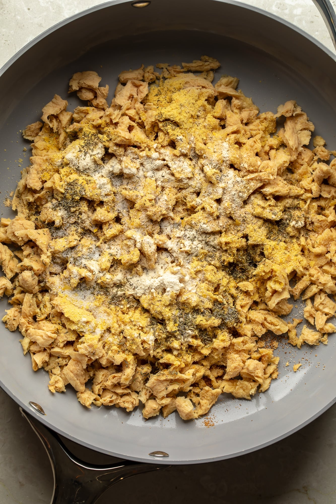 overhead view of seasoned soy curls cooking in a skillet for spicy peanut vegan "chicken" noodles.
