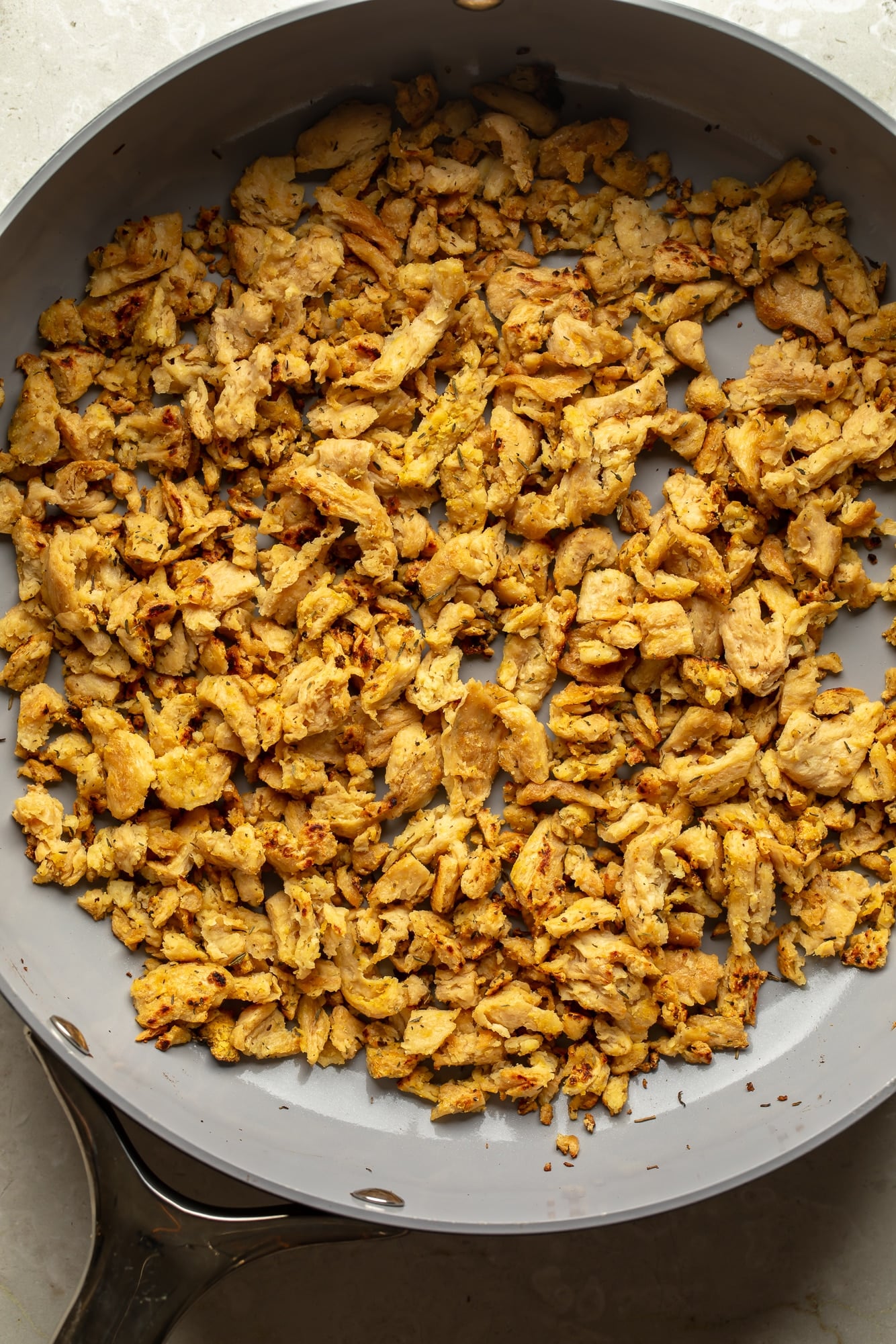 overhead view of cooked soy curls in a skillet for spicy peanut vegan "chicken" noodles.