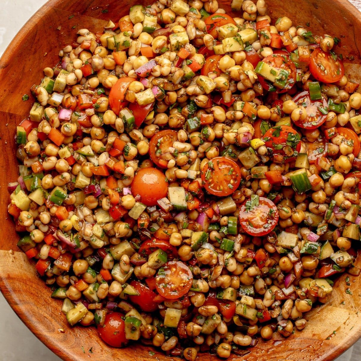 overhead view of a dense bean salad in a large bamboo bowl.