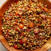 overhead view of a dense bean salad in a large bamboo bowl.