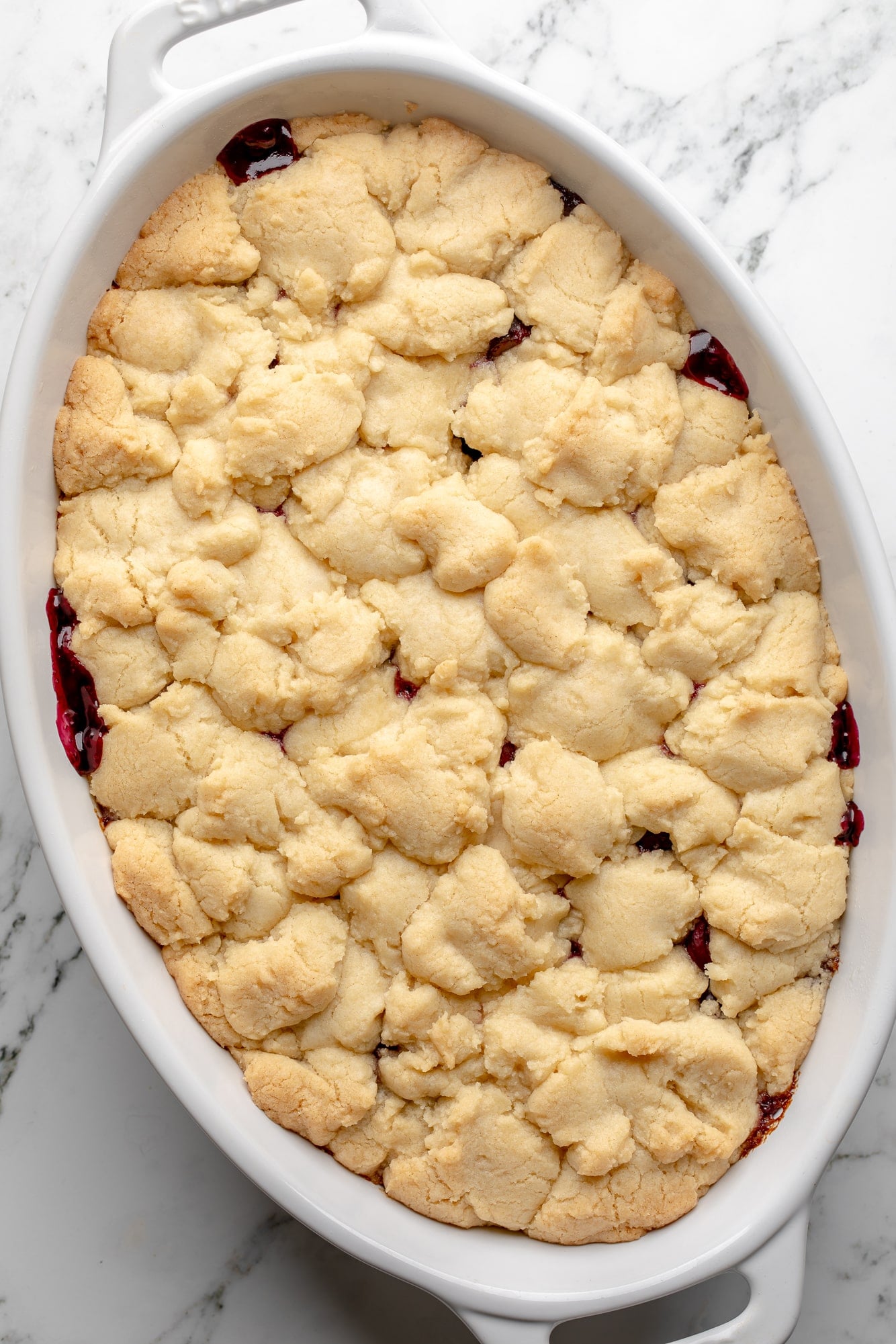 overhead view of a baked vegan cherry cobbler in a large baking dish.