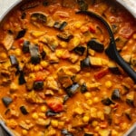 overhead view of roasted eggplant curry simmering in a large skillet.