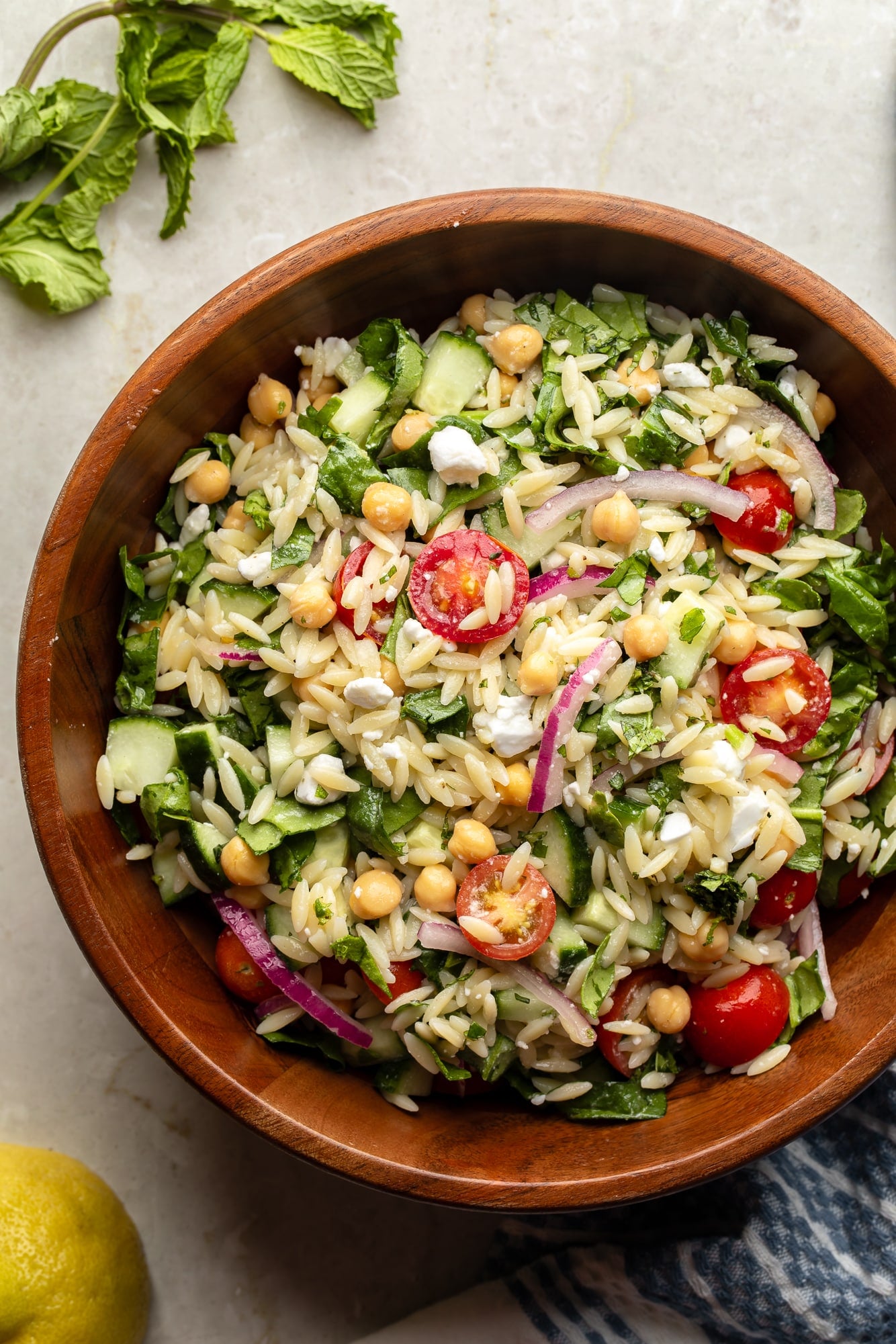 overhead view of a lemon orzo pasta salad in a large bamboo bowl.