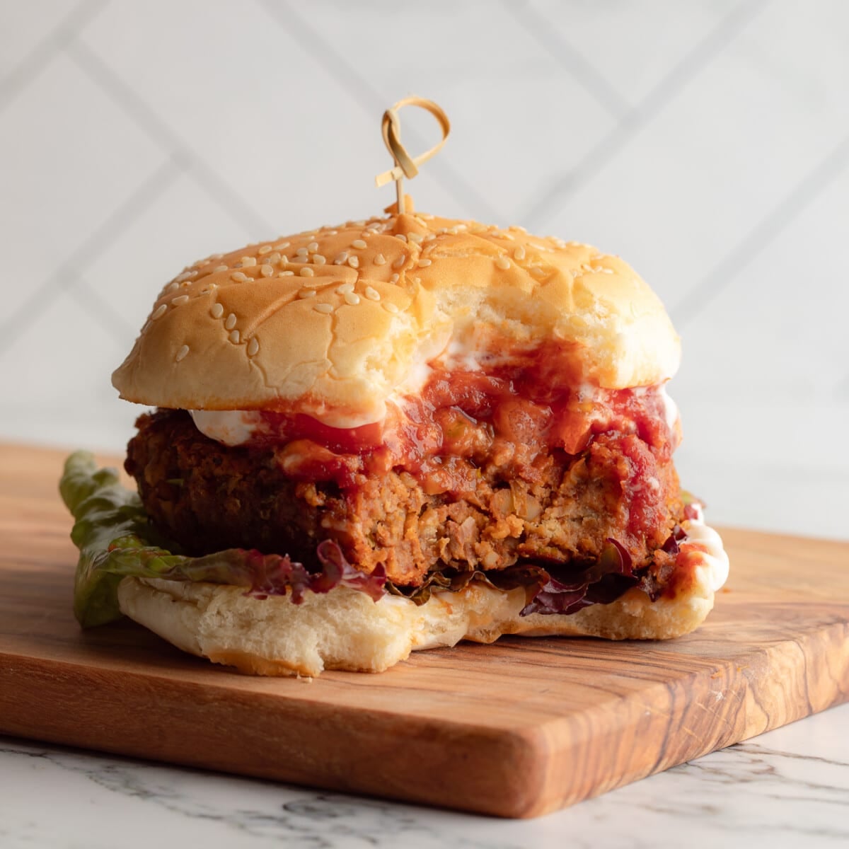 side view of a lentil burger on a bun with a bite taken out of it.