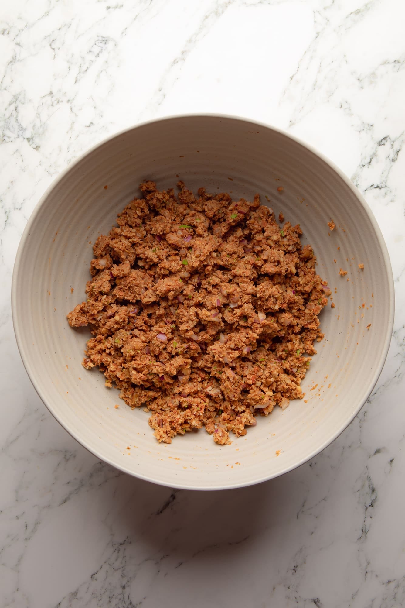 overhead view of the mashed lentil mixture for lentil burgers in a large bowl.