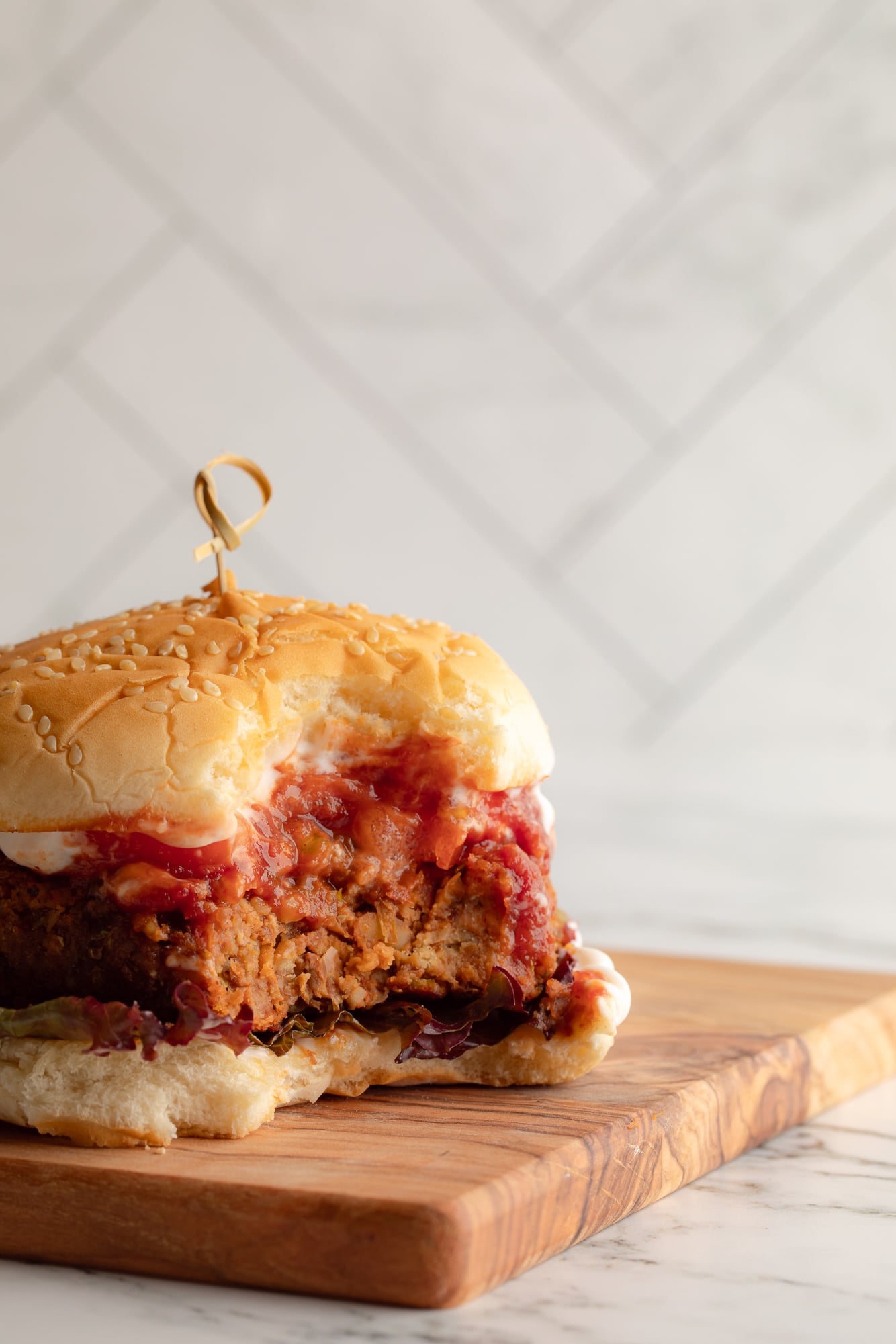 side view of a lentil burger on a bun with a bite taken out of it.
