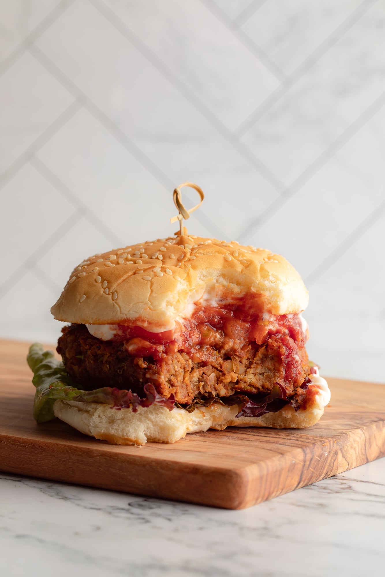 side view of a lentil burger on a bun with a bite taken out of it.