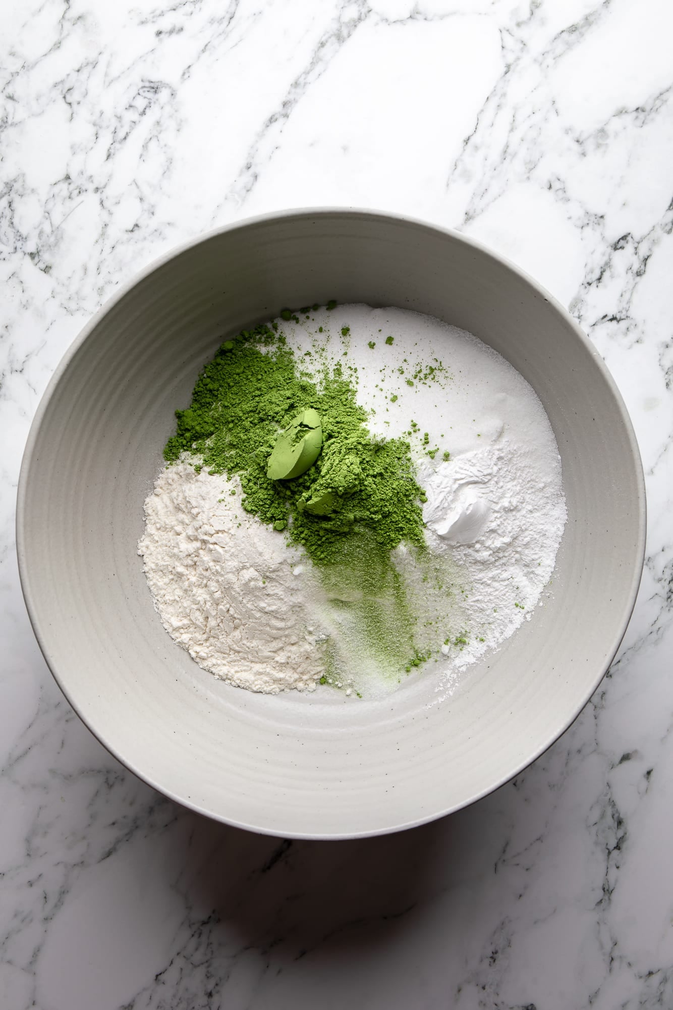 overhead view of the dry ingredients for vegan strawberry matcha cake in a large bowl.