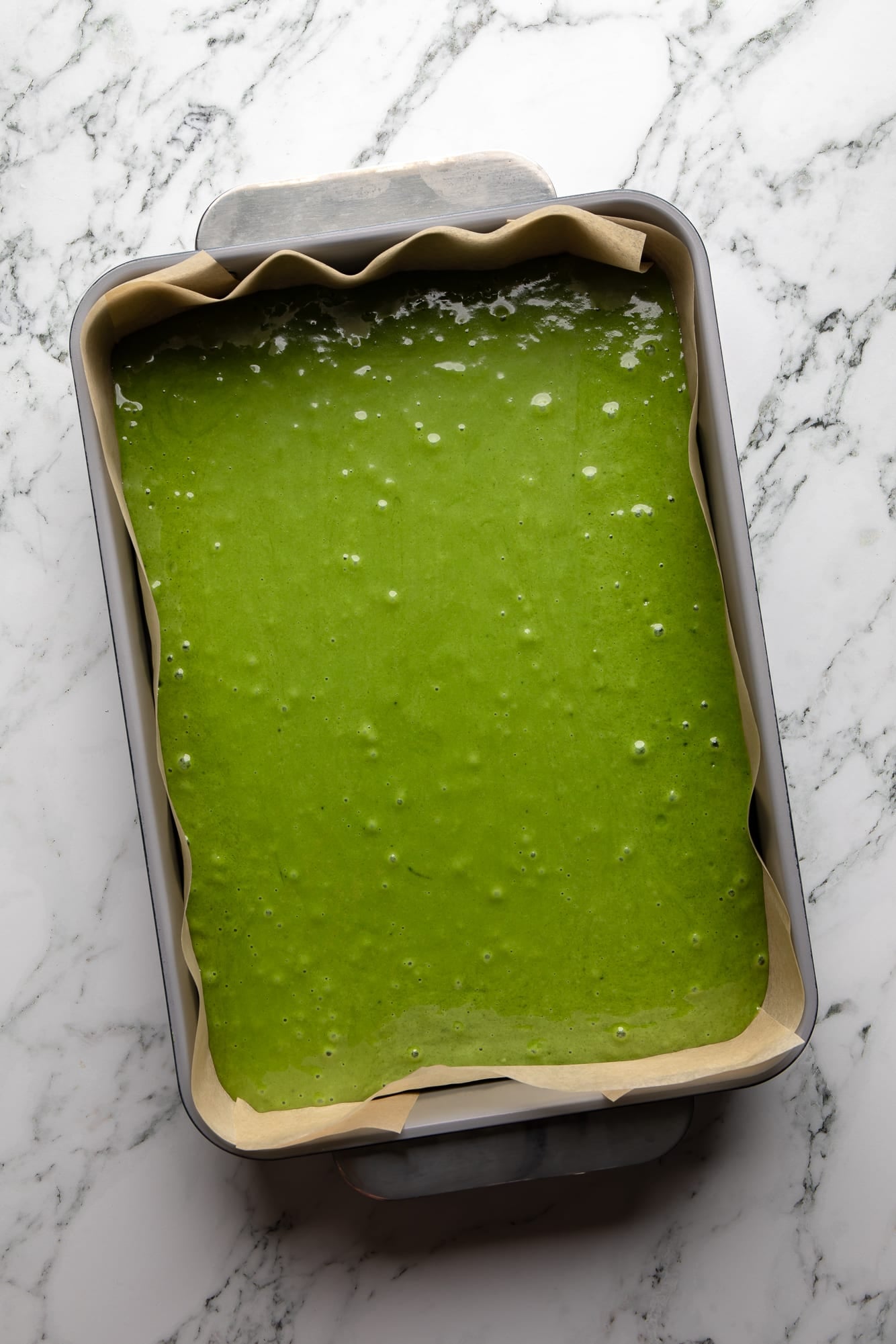 overhead view of the green cake batter for vegan strawberry matcha cake in a cake pan.