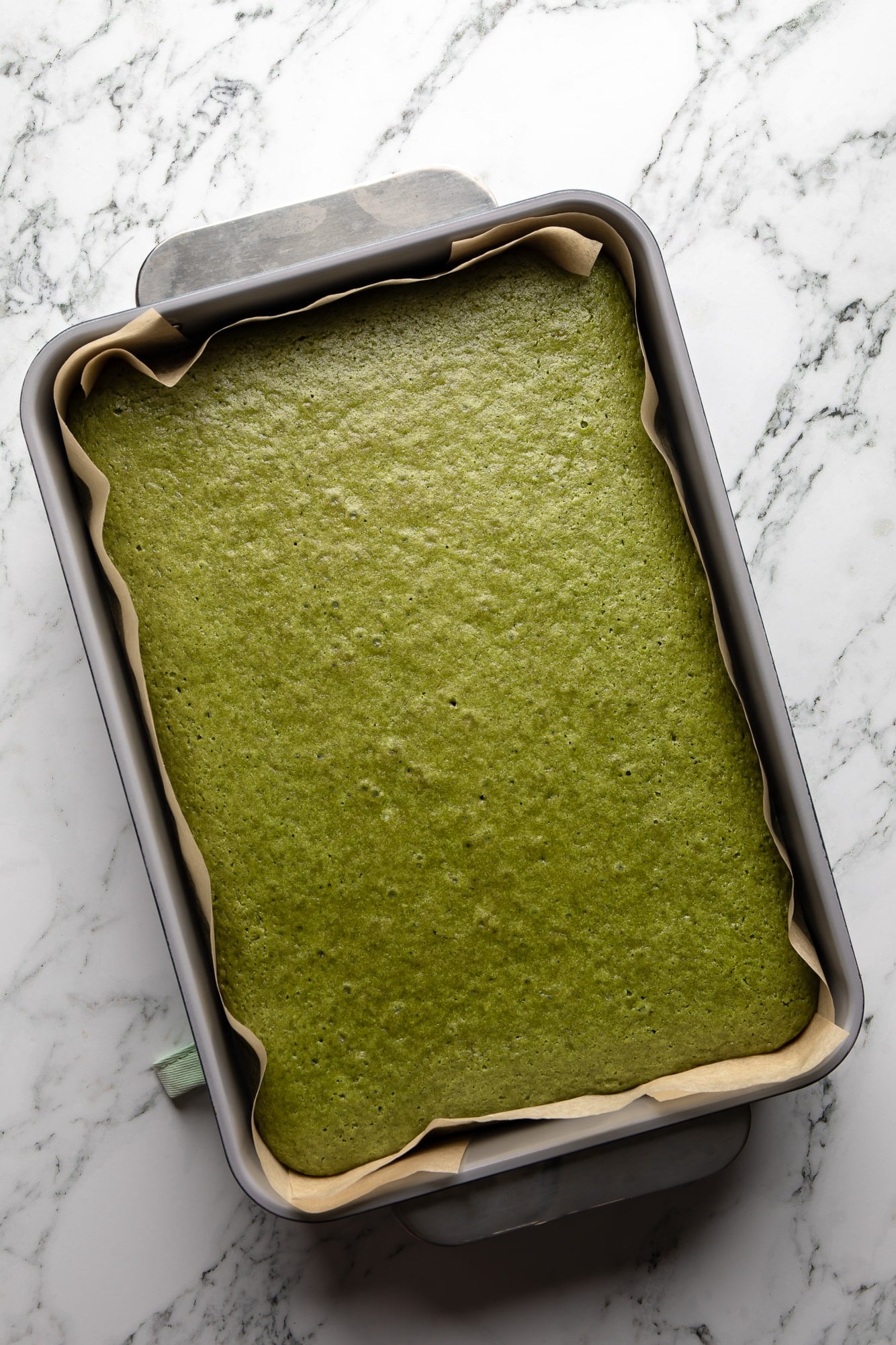 overhead view of a baked vegan strawberry matcha cake in a cake pan.