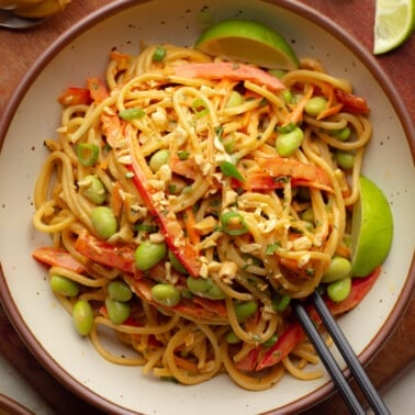 overhead view of vegan Thai peanut noodles in a bowl with black chopsticks.