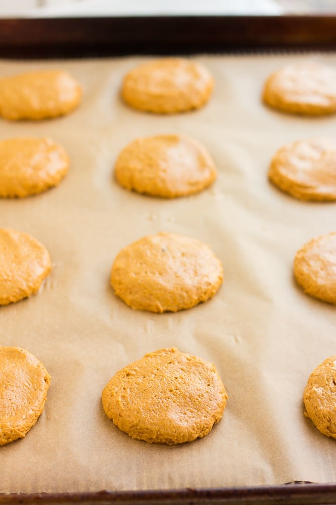 side view of unbaked vegan pumpkin cookies on a parchment-lined baking sheet.