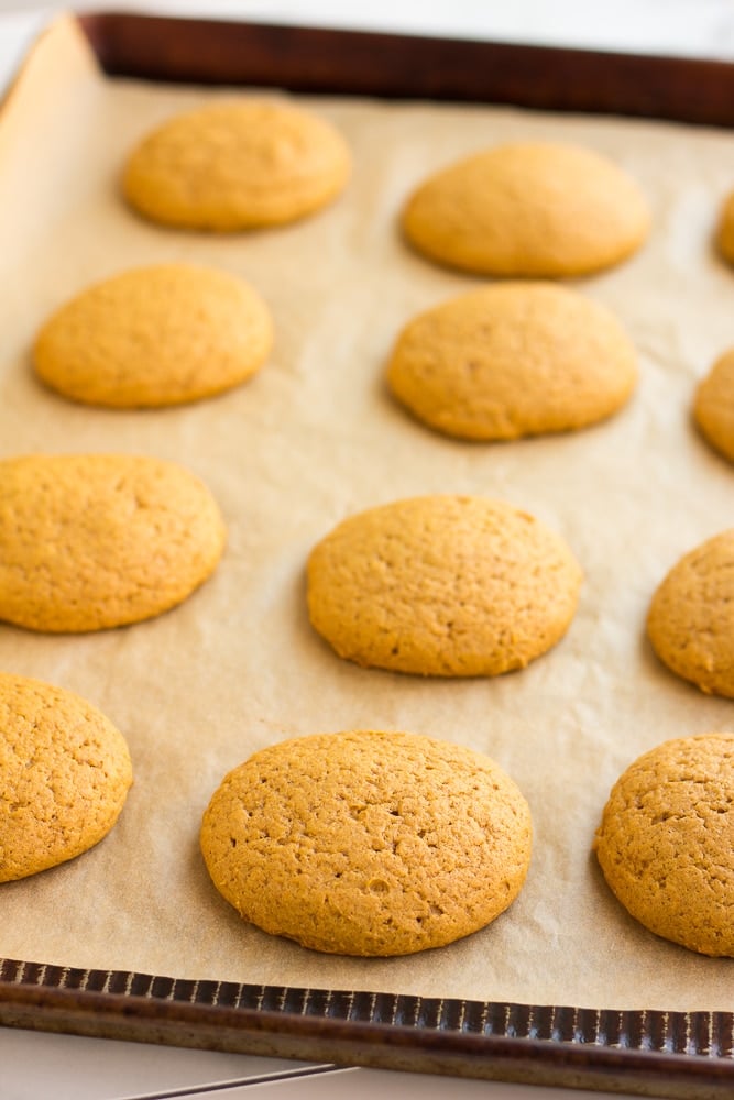 side view of baked vegan pumpkin cookies on a parchment-lined baking sheet.