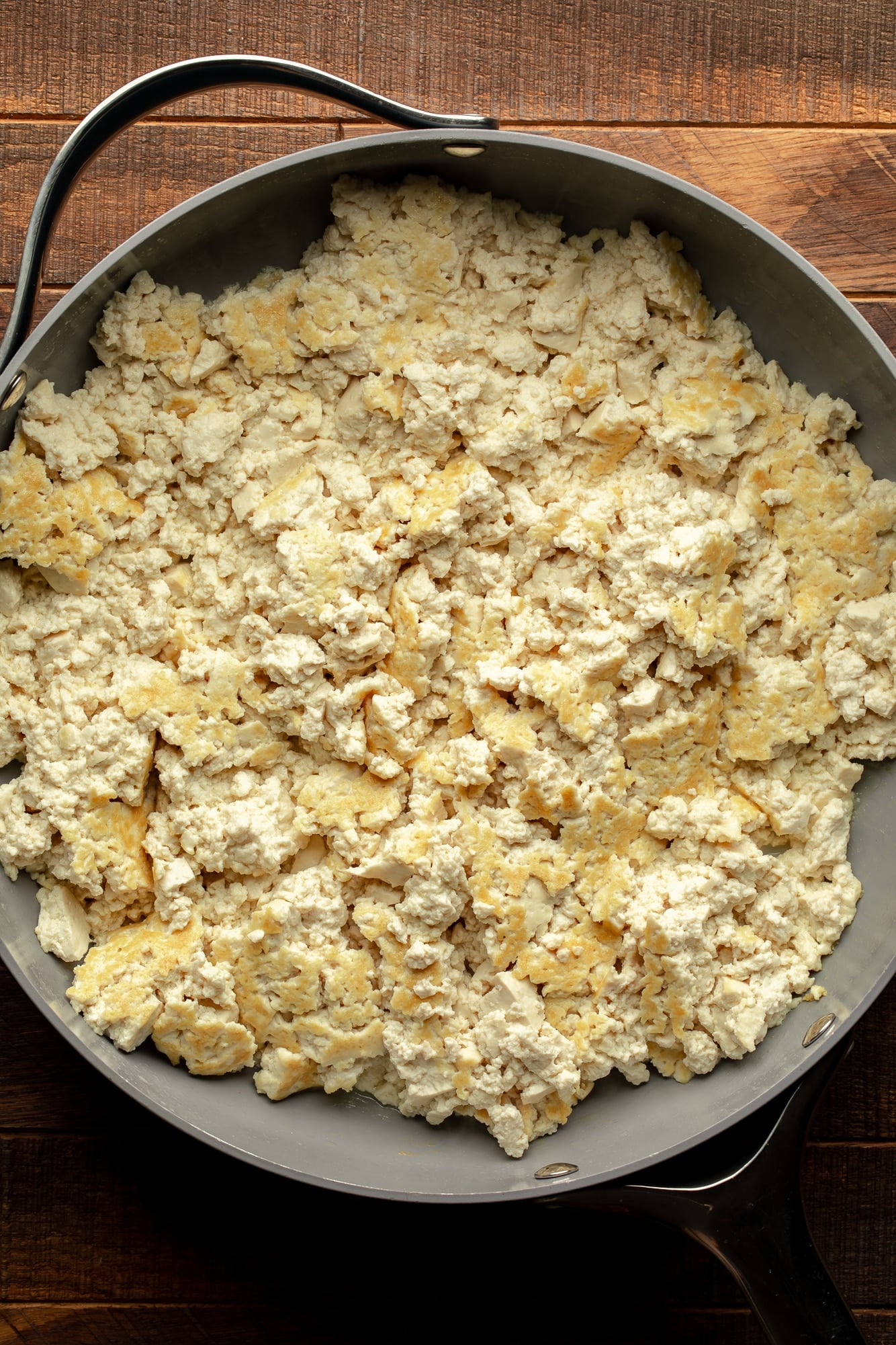 overhead view of crumbled tofu pan-frying in a large skillet.