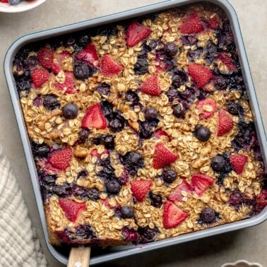 square image of baked berry oatmeal in a square baking pan.