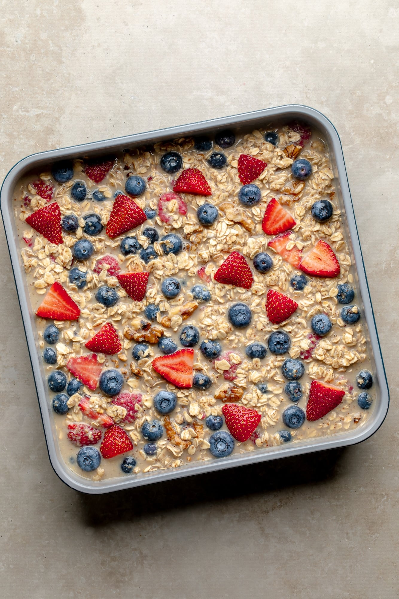 overhead view of unbaked berry oatmeal in a square baking pan.