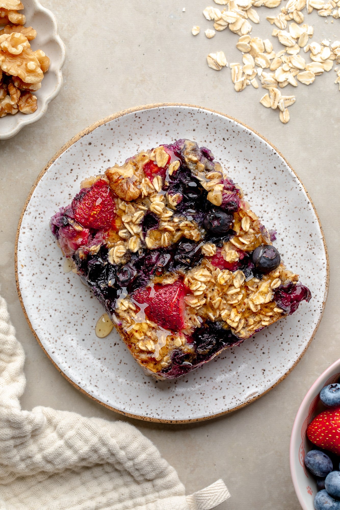 overhead view of a slice of baked berry oatmeal on a speckled plate.