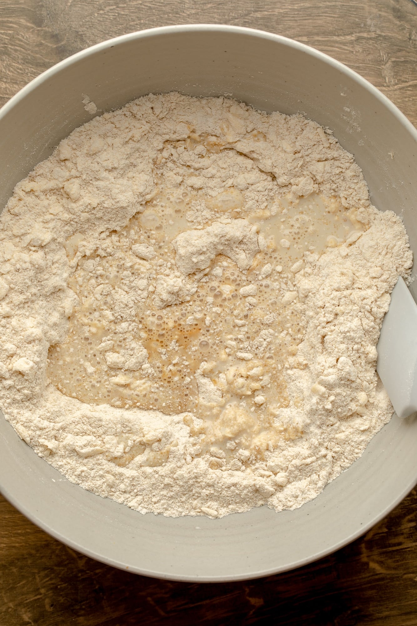 overhead view of the ingredients for maple pecan scone dough being mixed together in a large bowl.
