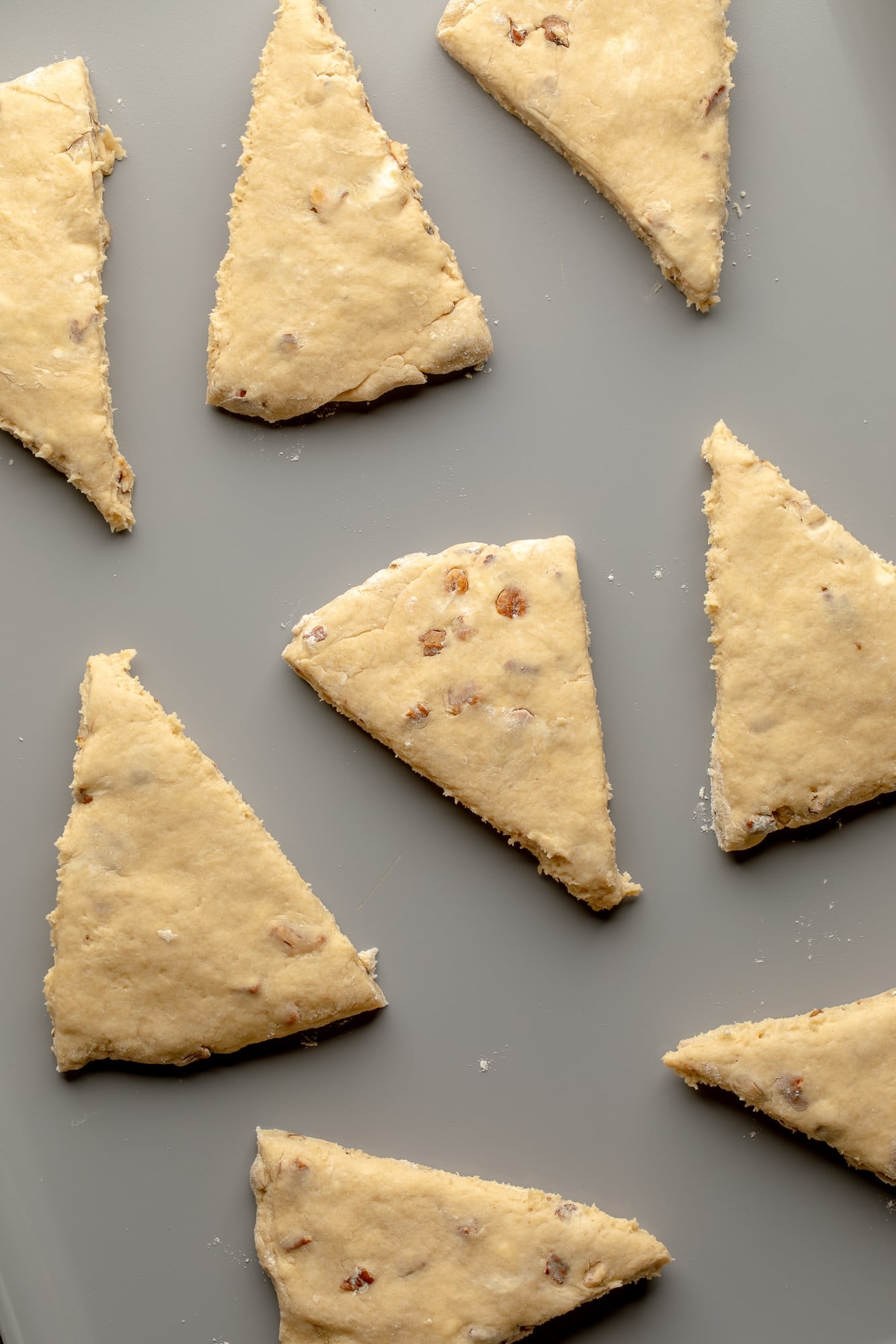 overhead view of maple pecan scone dough triangles in rows on a baking sheet.
