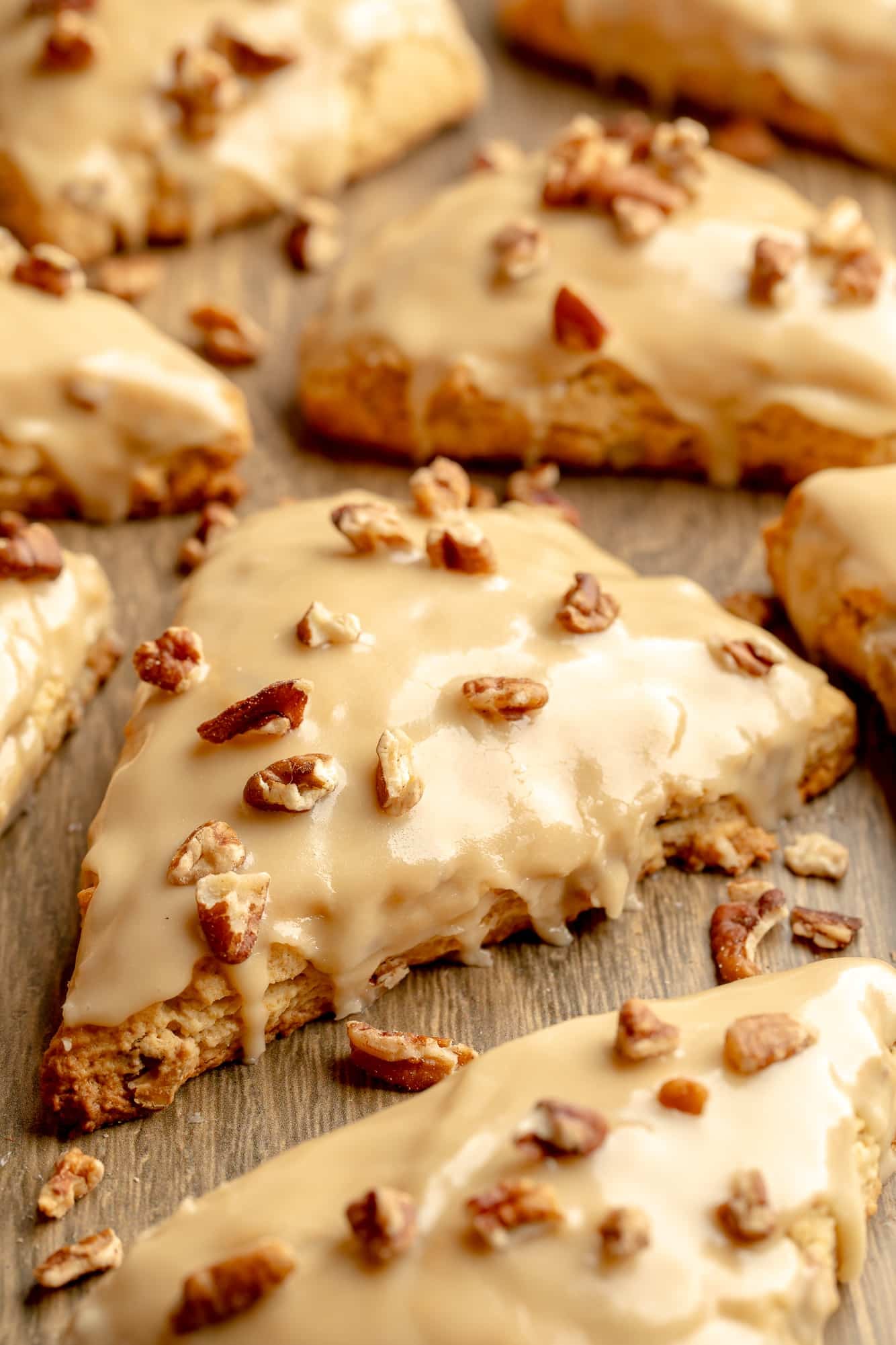 side view of vegan maple pecan scones topped with maple glaze and chopped pecans.