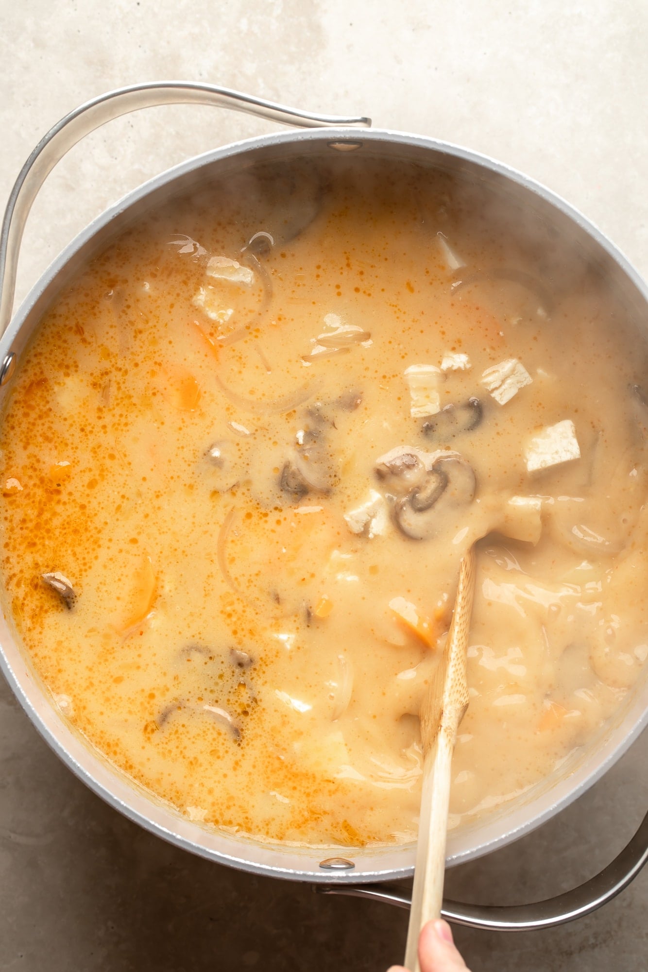 overhead view of a simmering pot full of Thai Coconut Soup (Vegan Tom Kha).
