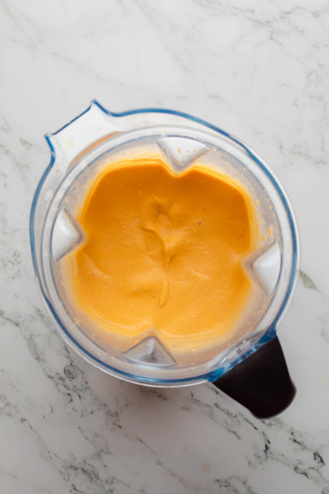 overhead view of an orange blended mixture for Tuscan white bean soup in a blender.