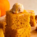 side view of a stack of 2 vegan pumpkin cornbread slices topped with a scoop of whipped maple cinnamon butter.