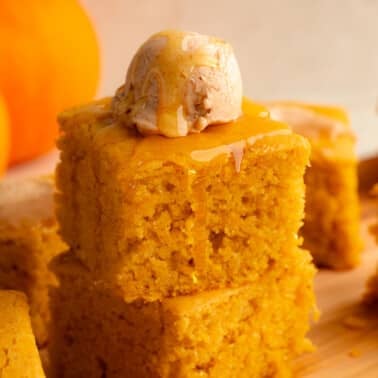 side view of a stack of 2 vegan pumpkin cornbread slices topped with a scoop of whipped maple cinnamon butter.