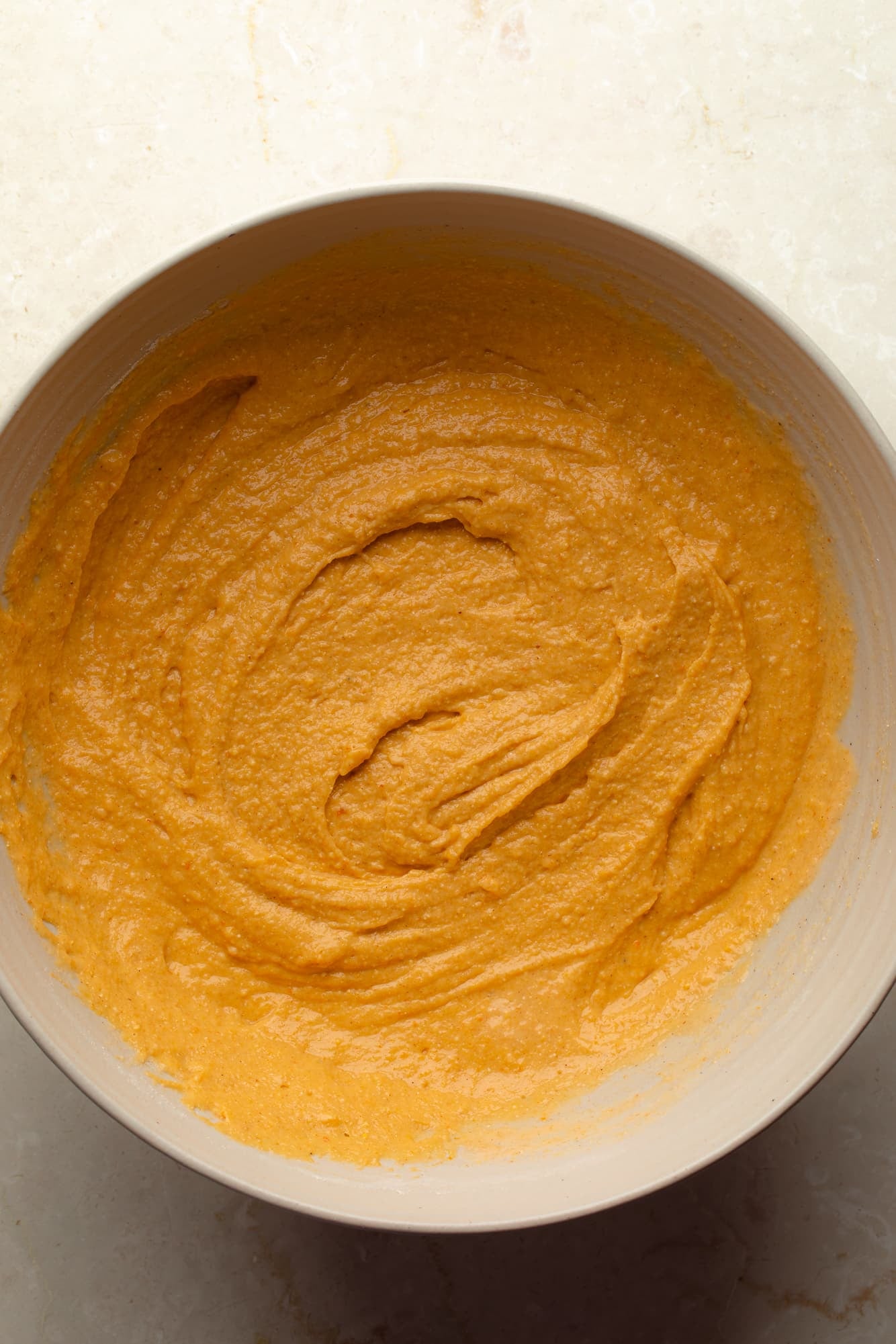 overhead view of the wet batter for vegan pumpkin cornbread in a bowl.