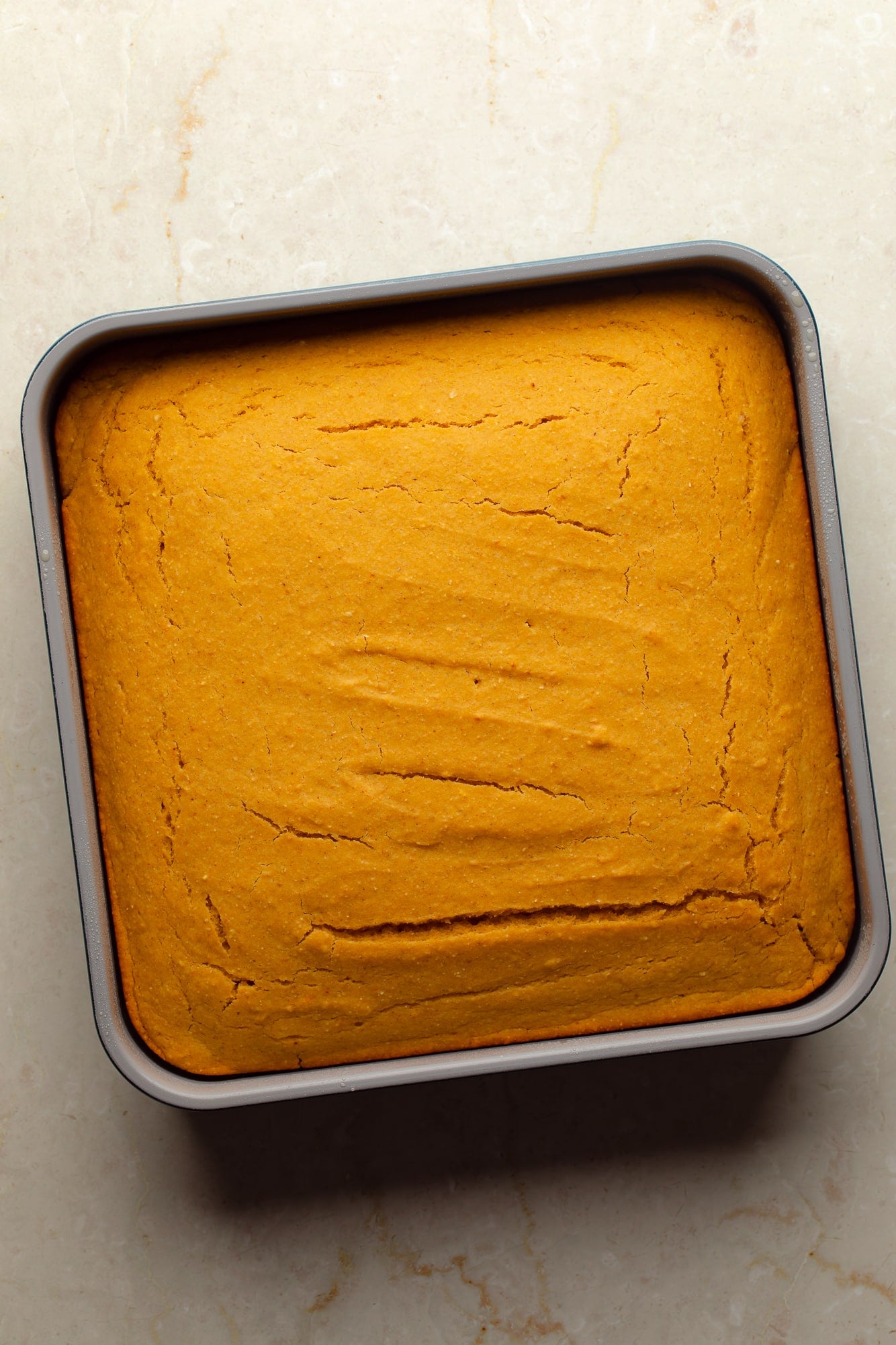 overhead view of baked vegan pumpkin cornbread in a square baking dish.