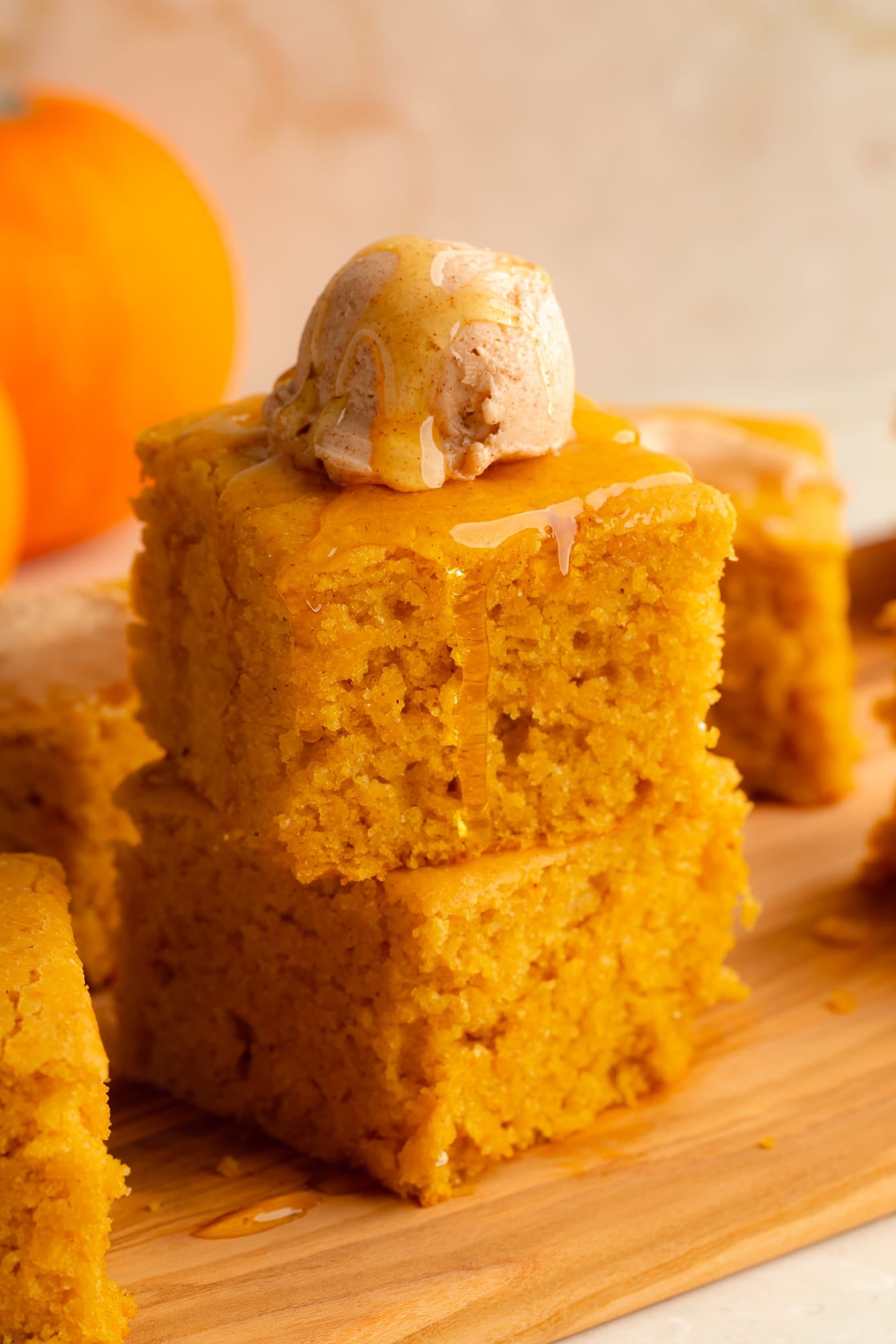side view of a stack of 2 vegan pumpkin cornbread slices topped with a scoop of whipped maple cinnamon butter.