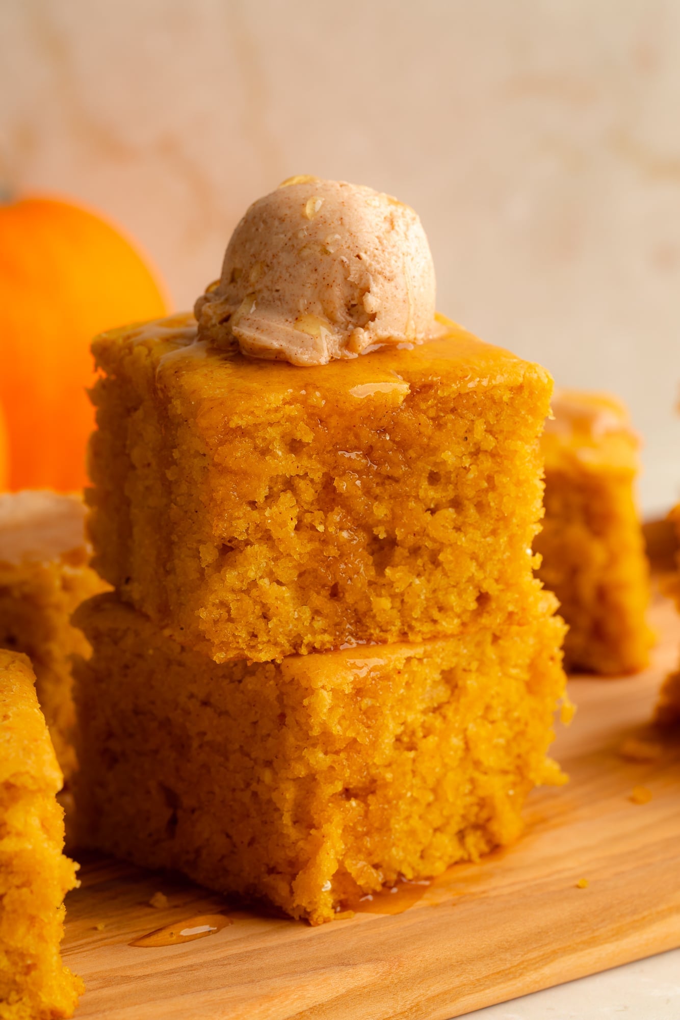 side view of a stack of 2 vegan pumpkin cornbread slices topped with a scoop of whipped maple cinnamon butter.